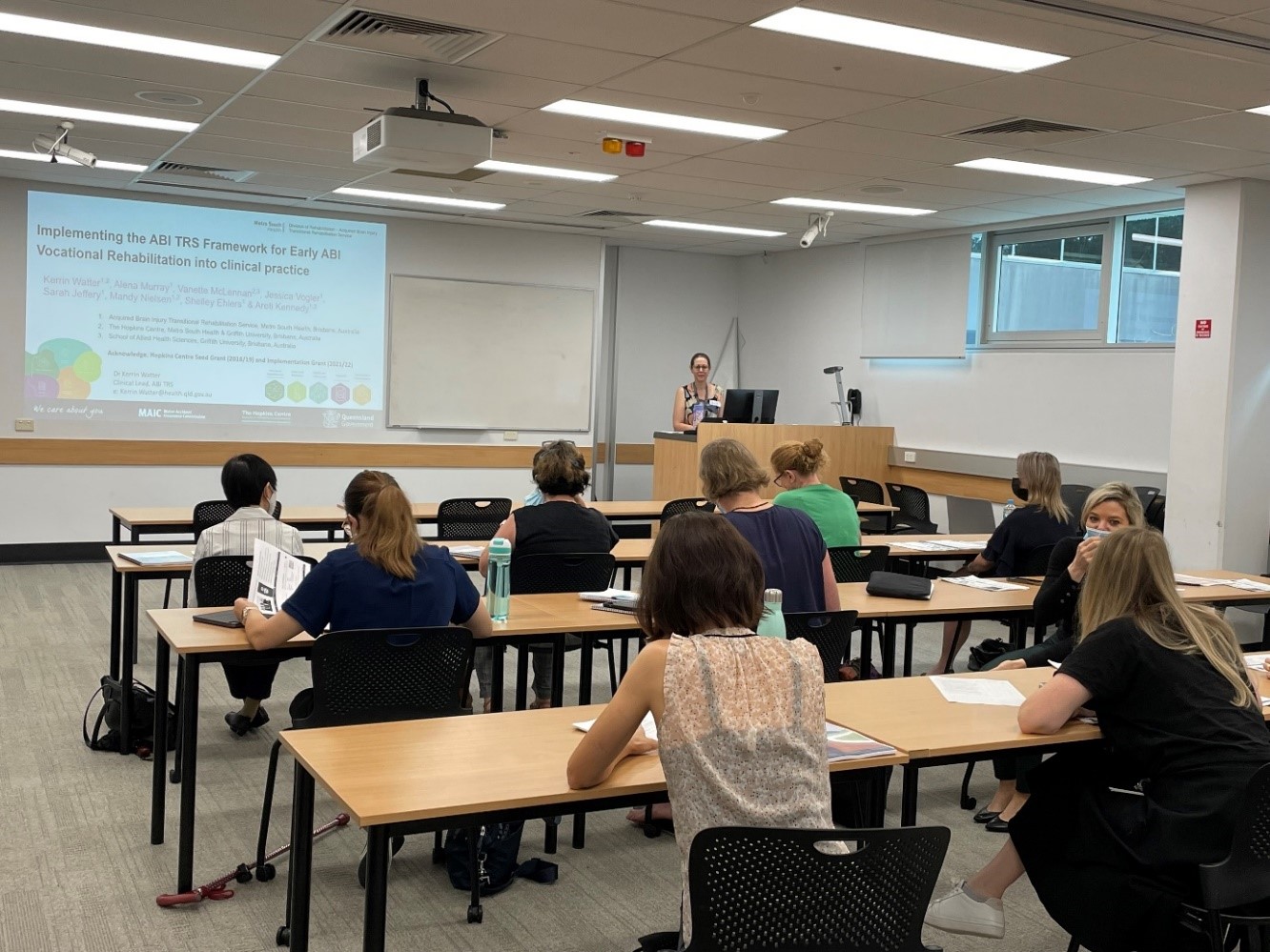 Workshop participants facing a projector screen and Kerrin Watter speaking at the front of the room.