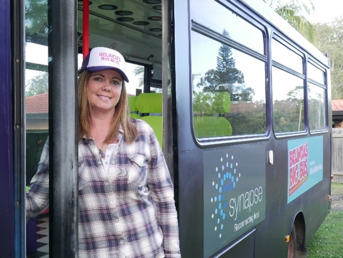 Belinda Adams standing next to her bus, with the Synapse logo on the side