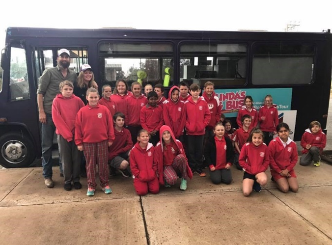 A group of young people in red uniforms in front of Belinda's bus