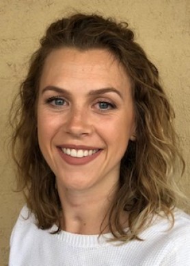 Emily Bray, a woman with sandy blonde wavy hair and a white knit jumper.