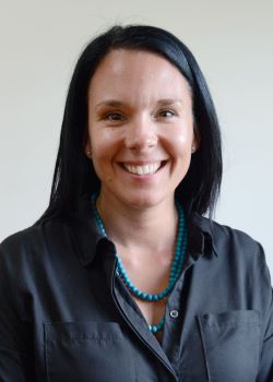 Sally Wooler, a woman with straight black hair wears a grey button-up shirt and beaded green necklace